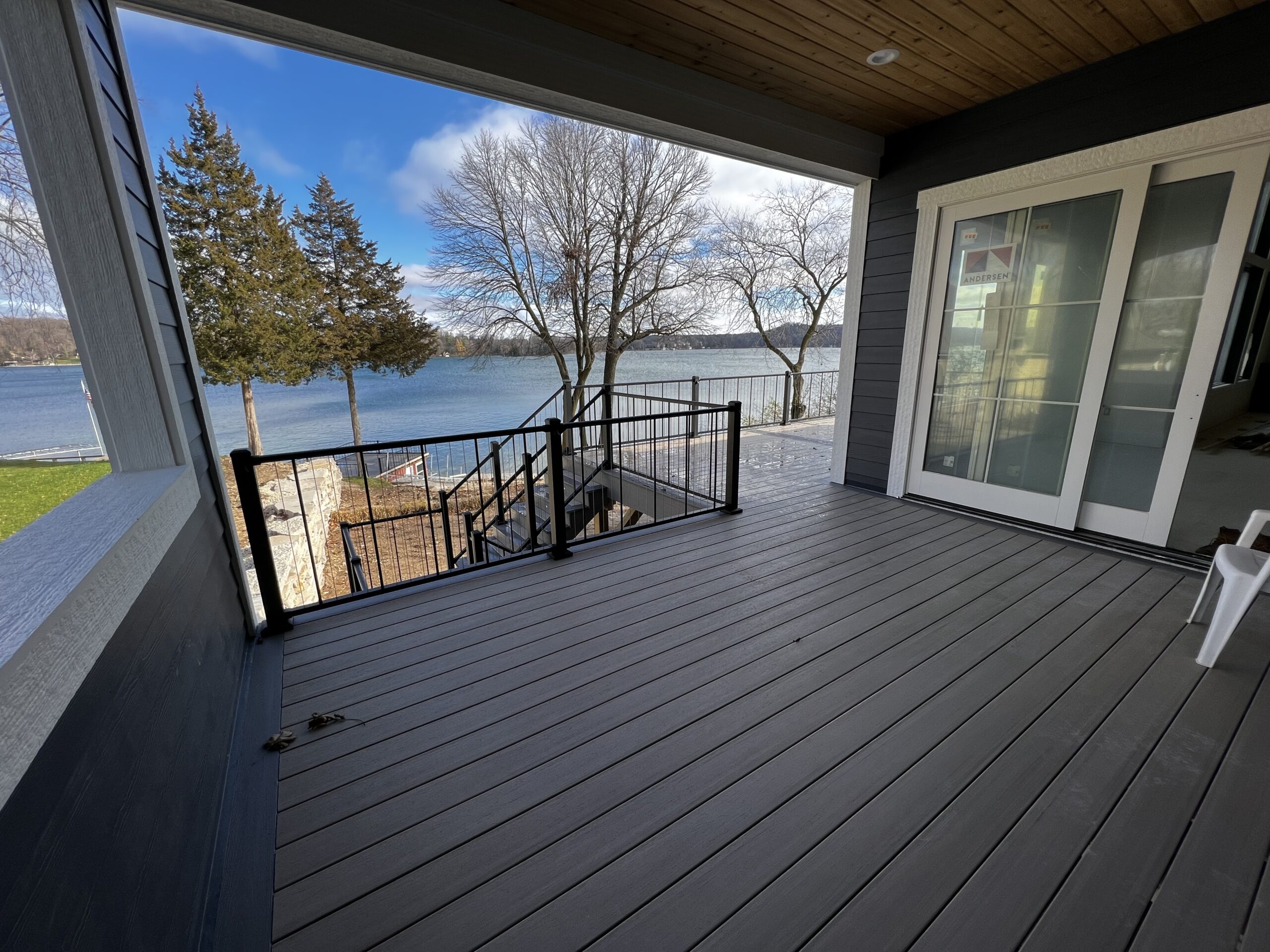 Photo of a Covered Composite Deck with Black Cable Railings and Deck Steps
