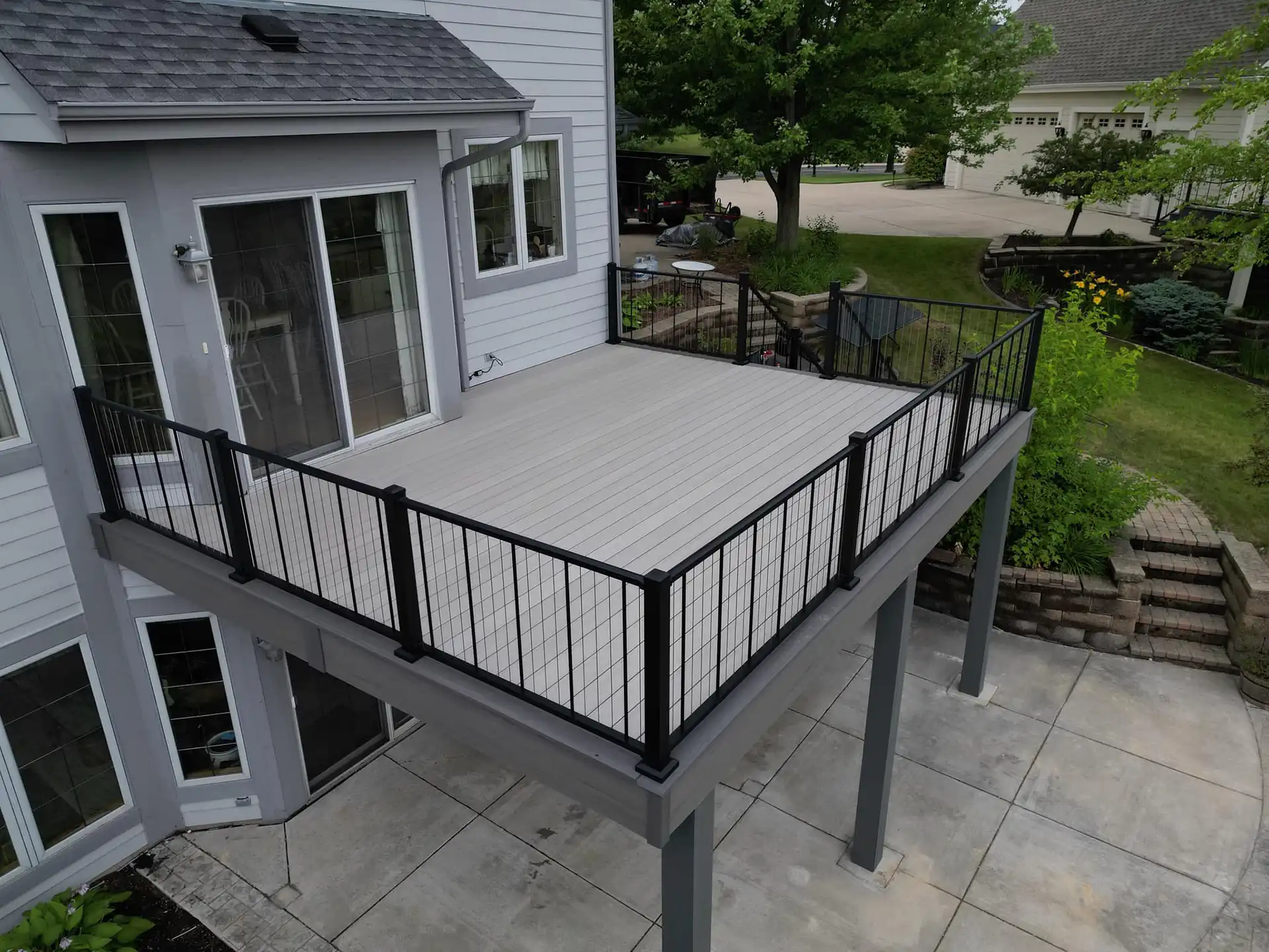 photo of an elevated composite deck with patio below - Materials and Design Considerations for Porches and Decks