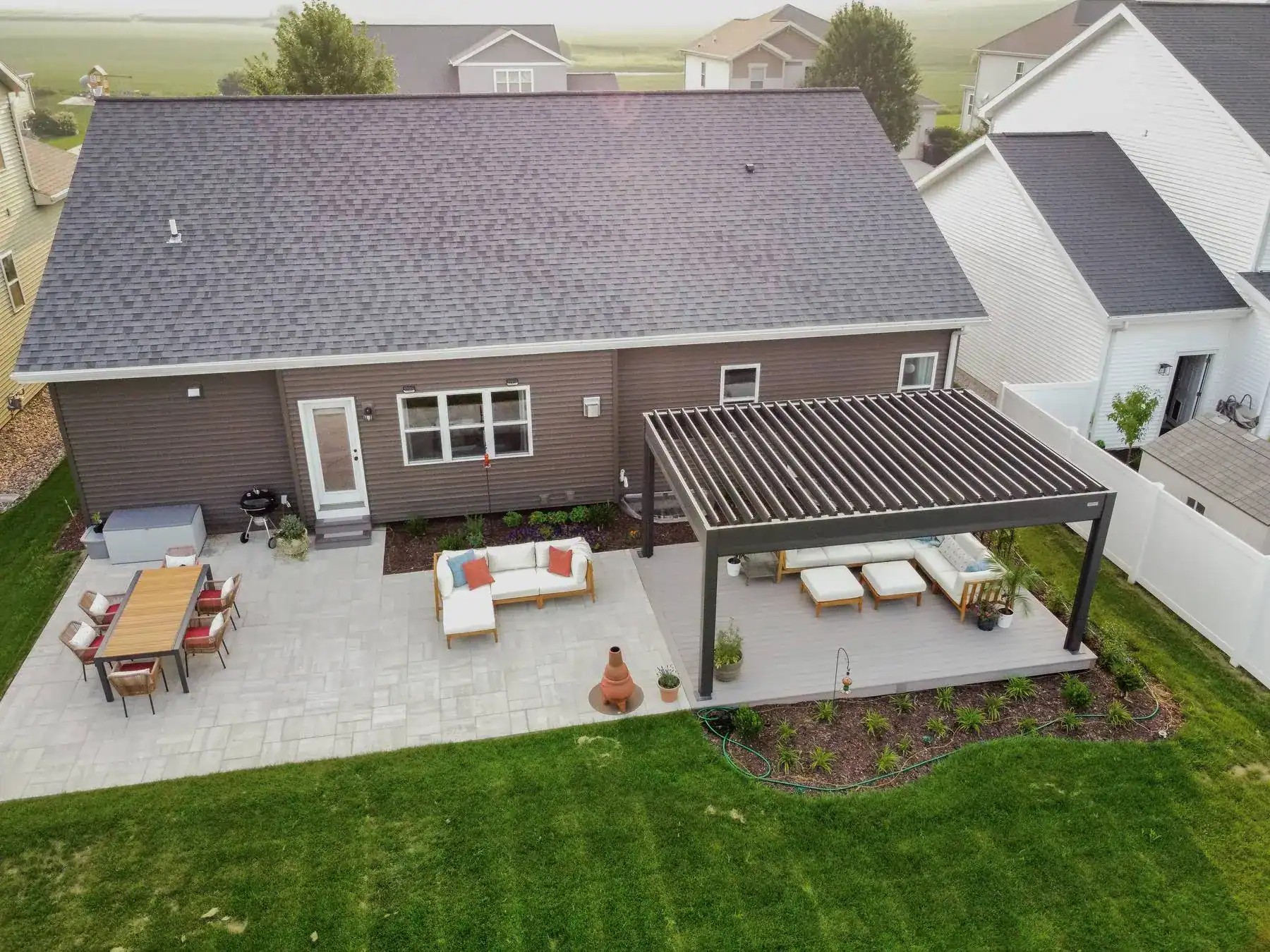 aerial view of a home with an attached patio and a ground level deck covered with a louvered pergola
