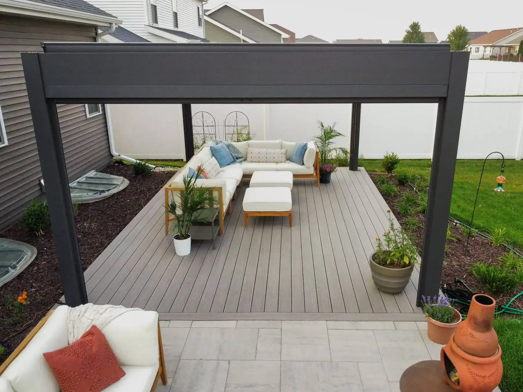 composite deck with a motorized louvered pergola featuring couches and plants