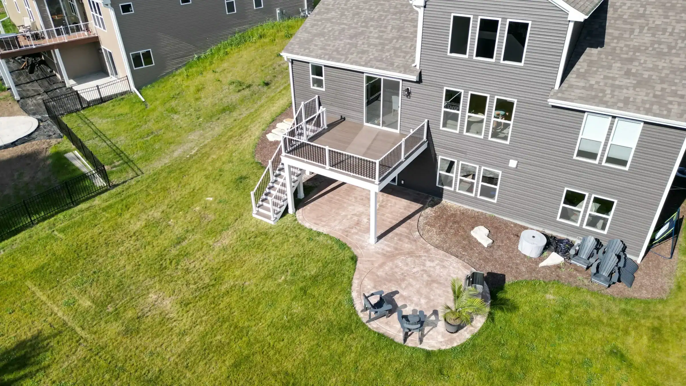 elevated deck with an attached patio featuring a grill and two chairs