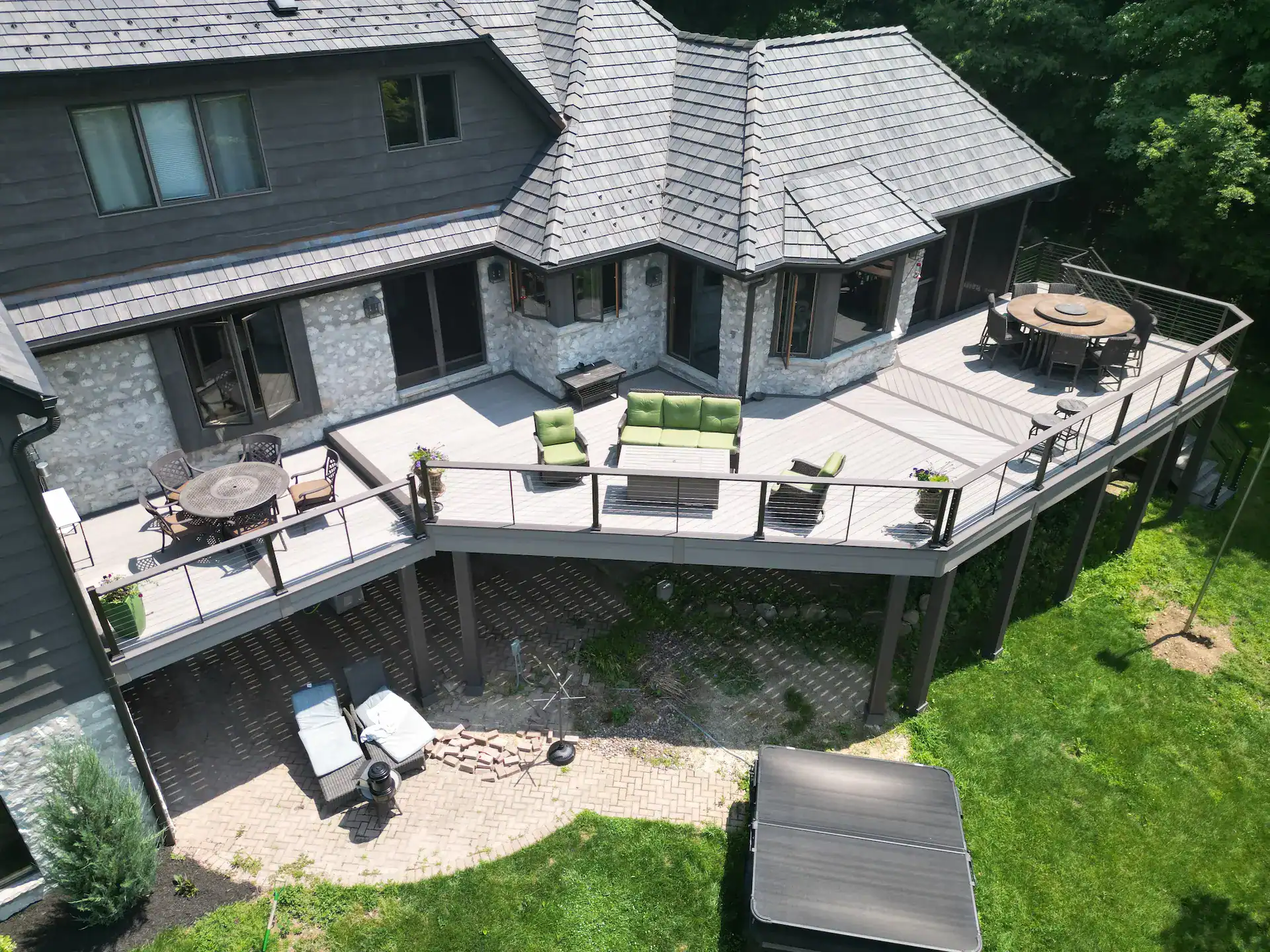 two story home with an elevated pvc deck with a metal and cable railing and an attach patio