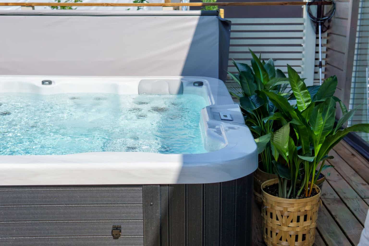 stock outdoor hot tub on wooden deck with privacy screen and potted plants