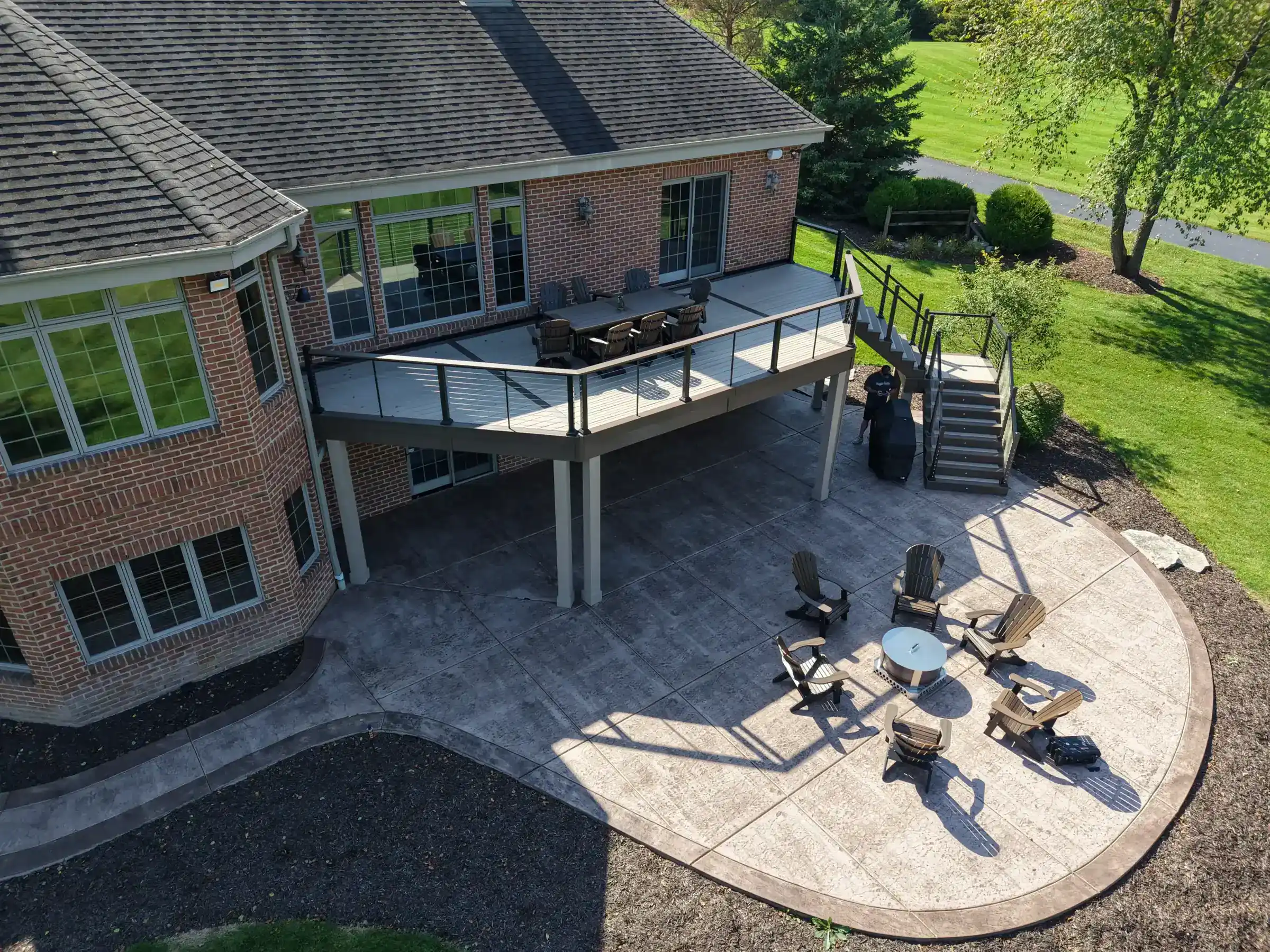 Aerial view of the attached patio with a firepit with outdoor chairs and elevated residential deck with outdoor living spaces in slinger wi