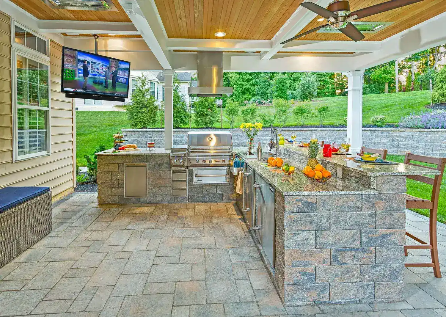 Elegant outdoor kitchen with a lot of fruits and a tv featuring overlooking nature view in slinger wi