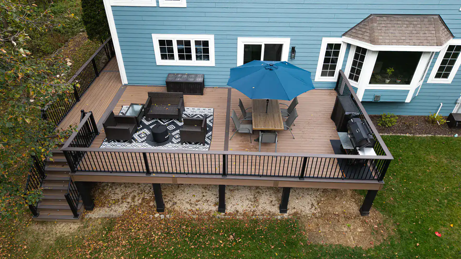Elevated light brown composite deck with outdoor living spaces with grill in slinger wi