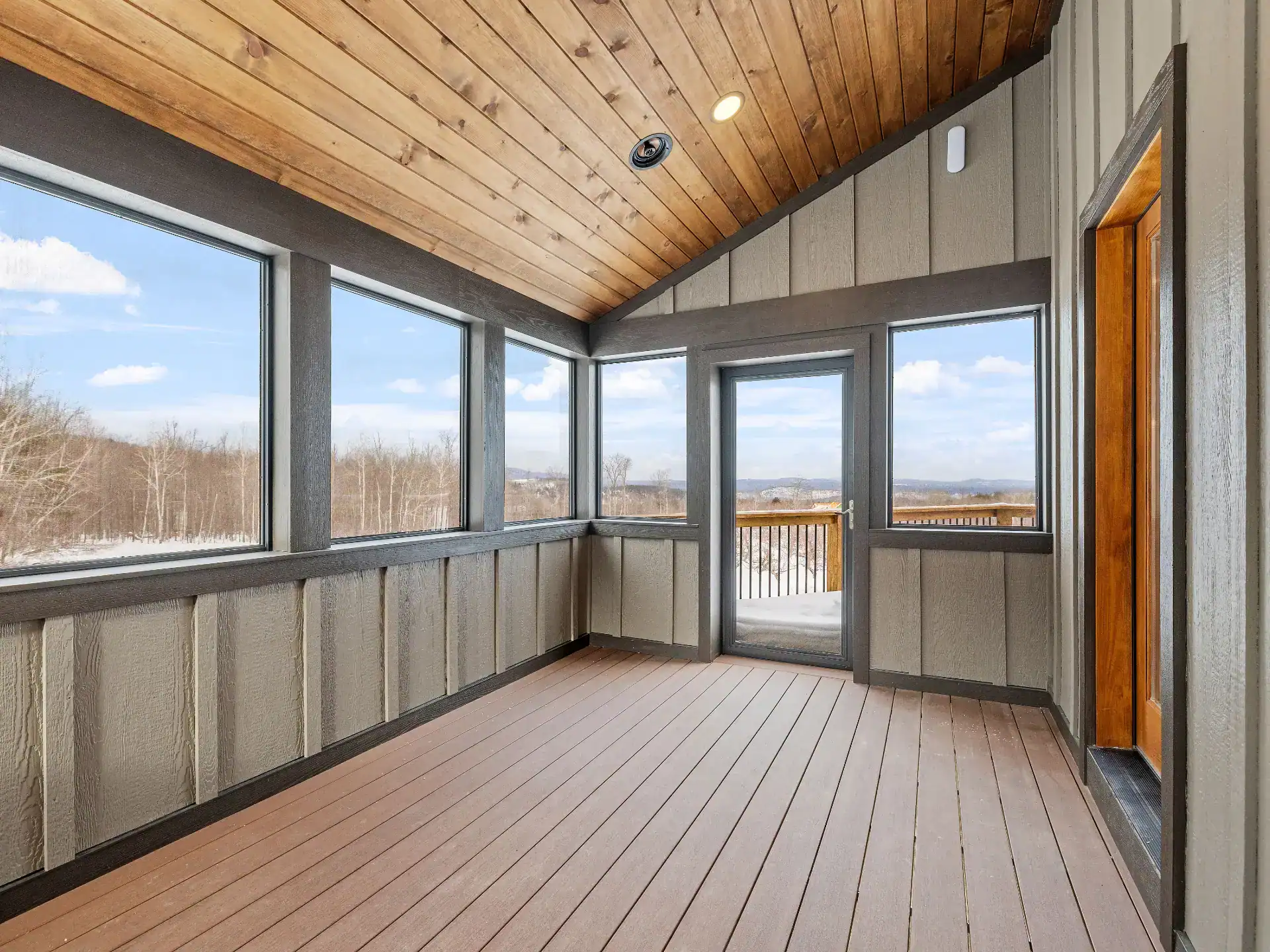 Empty balcony with doors and a sliding glass door with wooden ceiling and overlooking nature view in slinger wi