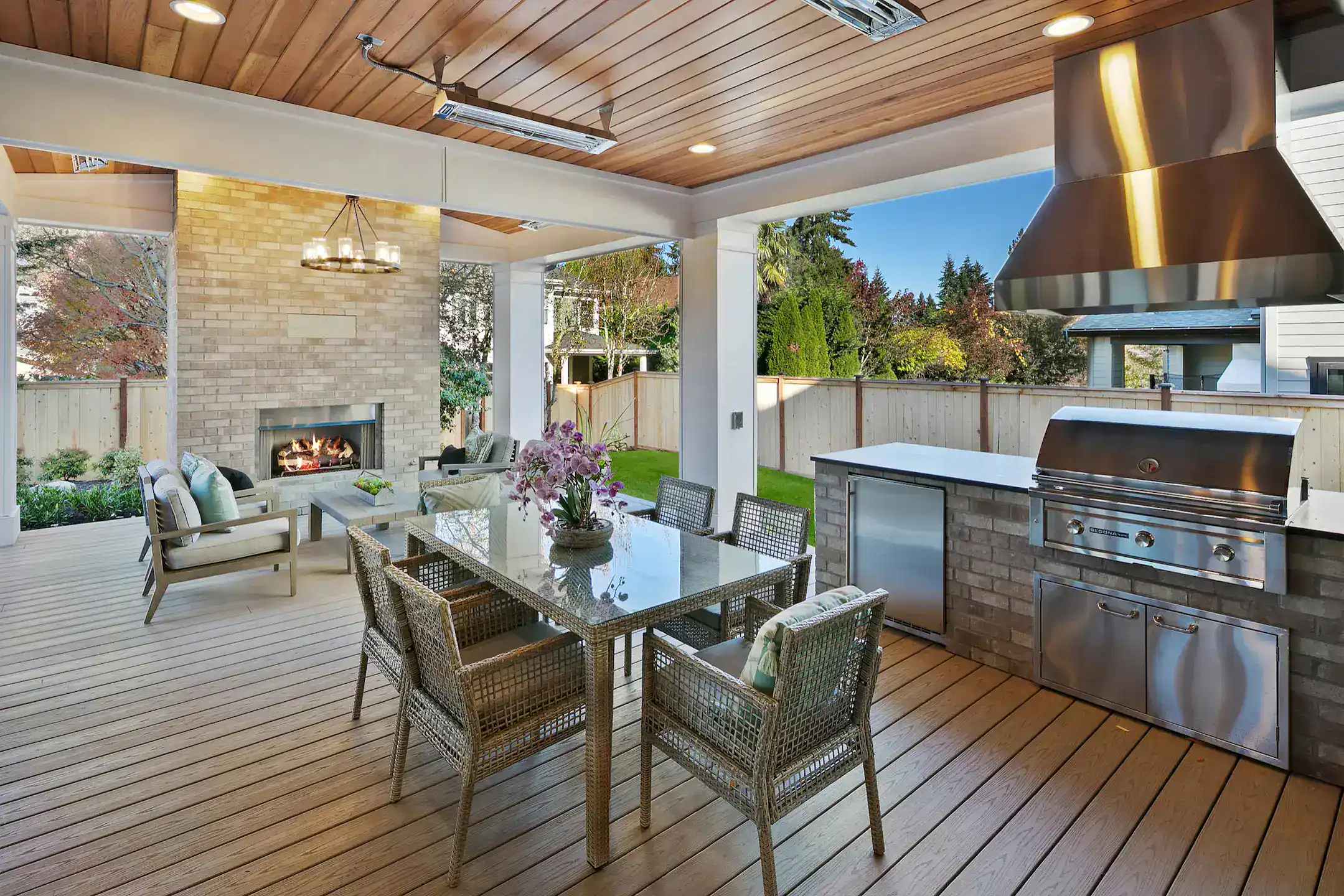 Fireplace and an outdoor kitchen in a deck with outdoor living furniture featuring wooden fence in slinger wi