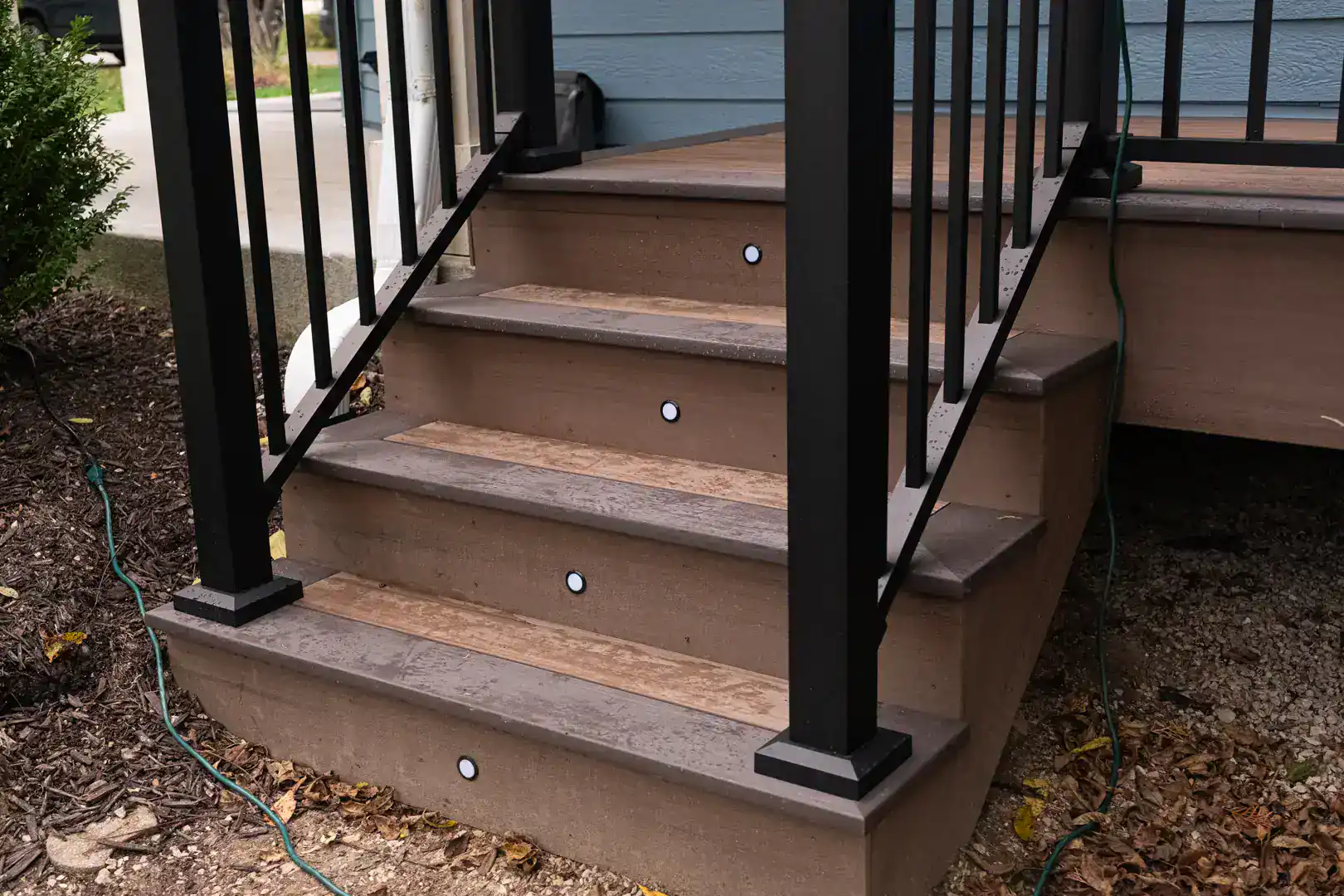 Raised deck with lights on stair steps with black metal railing in slinger wi