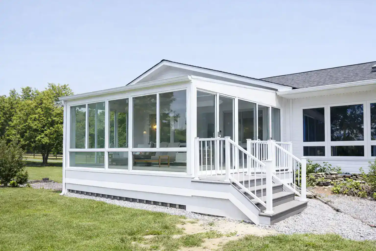 White porch enclosure on the raised deck with furniture inside in slinger wi