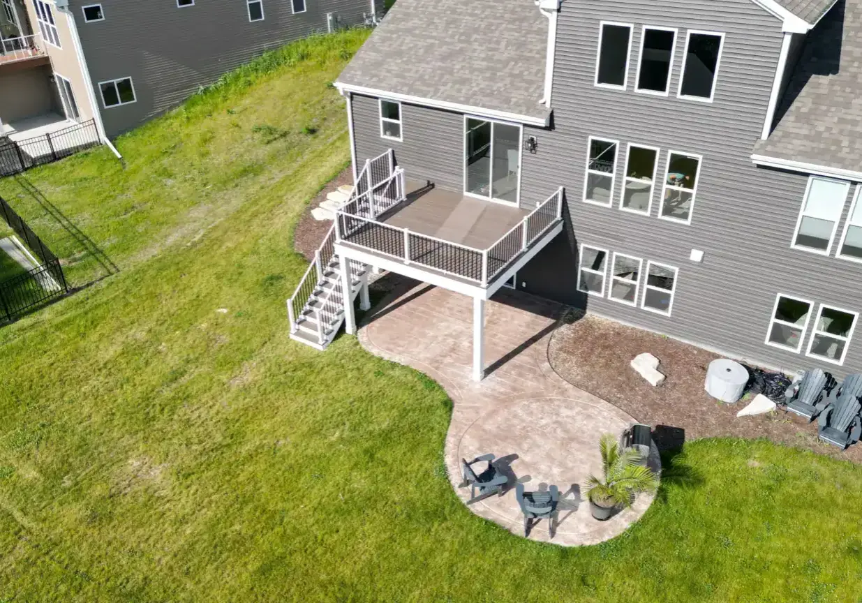 elevated deck with an attached patio featuring a grill and two chairs