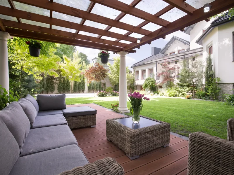 Text: Photo of a pergola with canopy covering a wood deck with outdoor furniture.